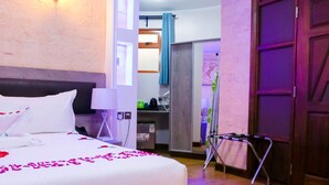 A hotel room with a large bed, a desk, a wardrobe, and a bathroom visible through an open door.