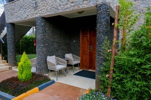 A stone-clad building with a wooden door, outdoor seating, and a small garden area.