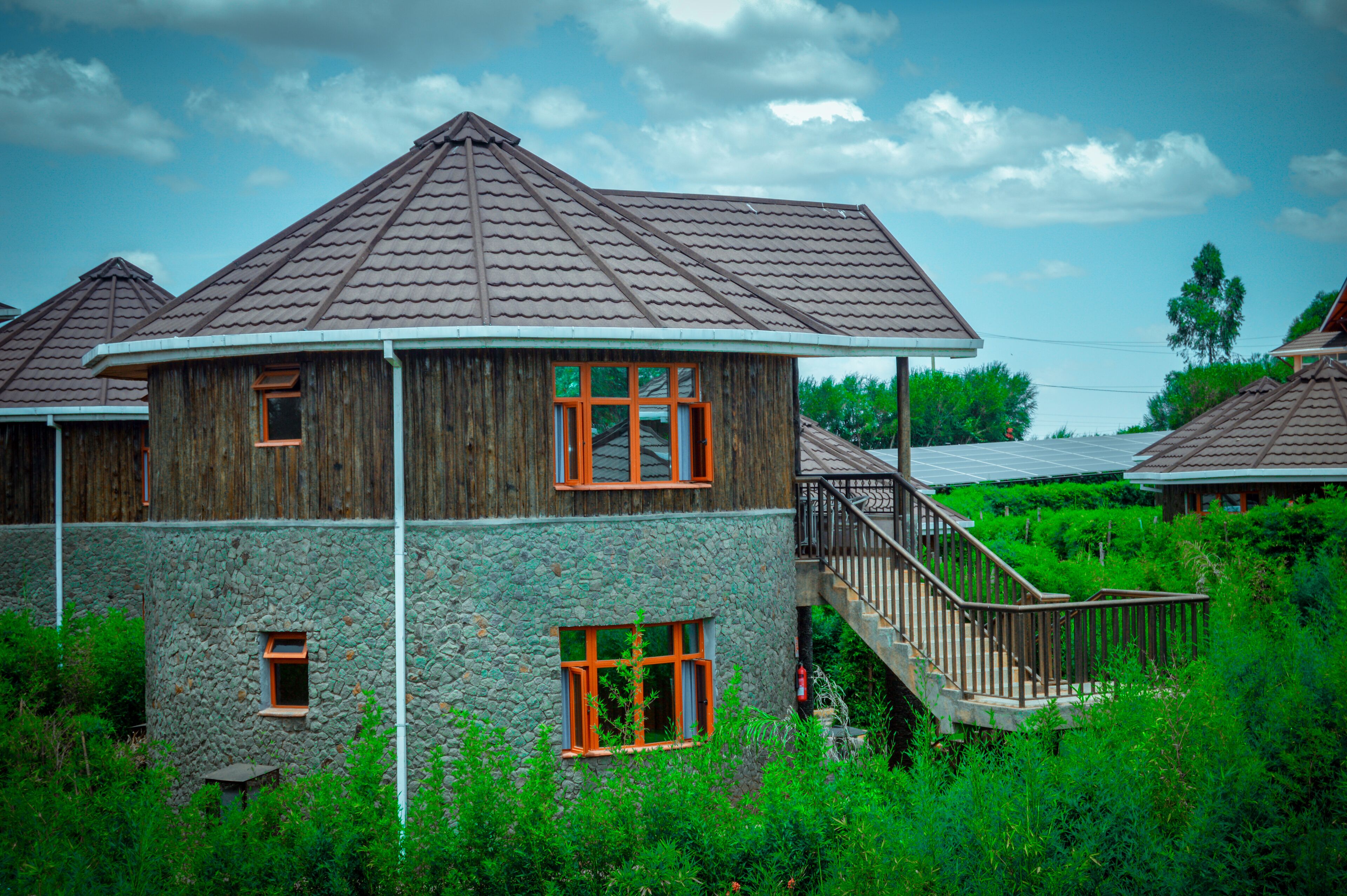 Ein Holzhaus mit Steinaußenwand, einem Balkon und einer Treppe, die zum Eingang führt.