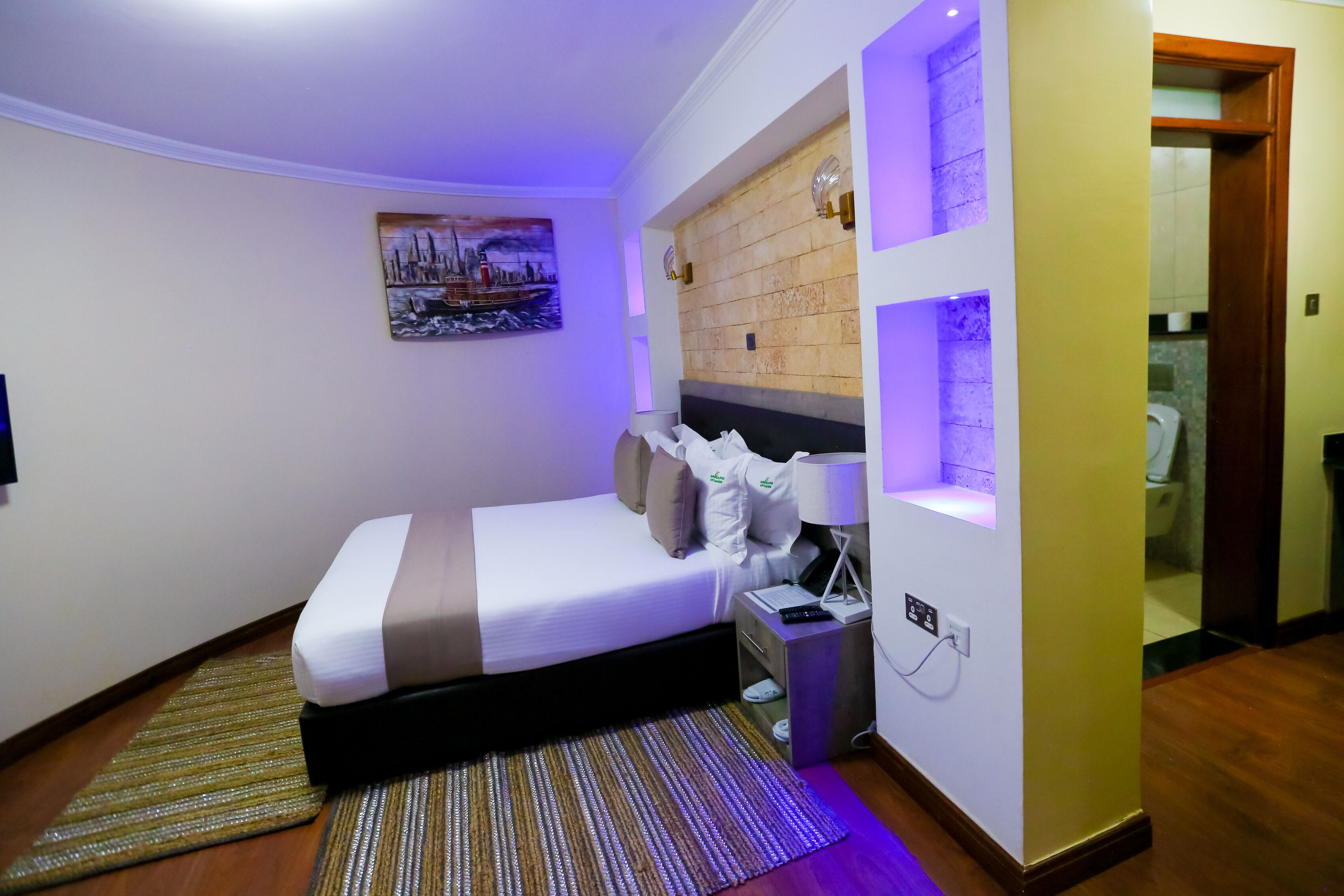 Une chambre bien rangée, avec un lit, une table de chevet et une étagère fixée au mur.