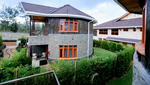 A two-story house with a stone facade, a balcony, and a well-maintained garden.