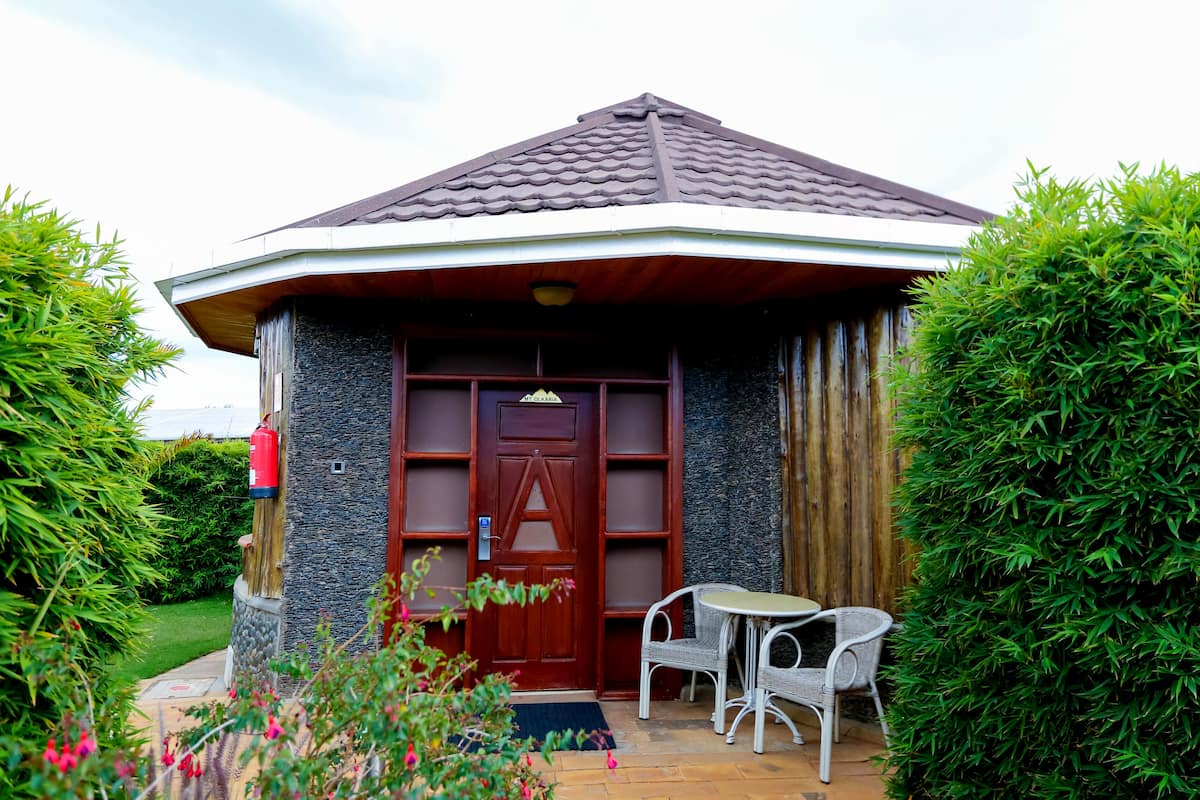 Un pequeño edificio de piedra con techo de tejas, puerta de madera y un pequeño espacio al aire libre con dos sillas y una mesa.
