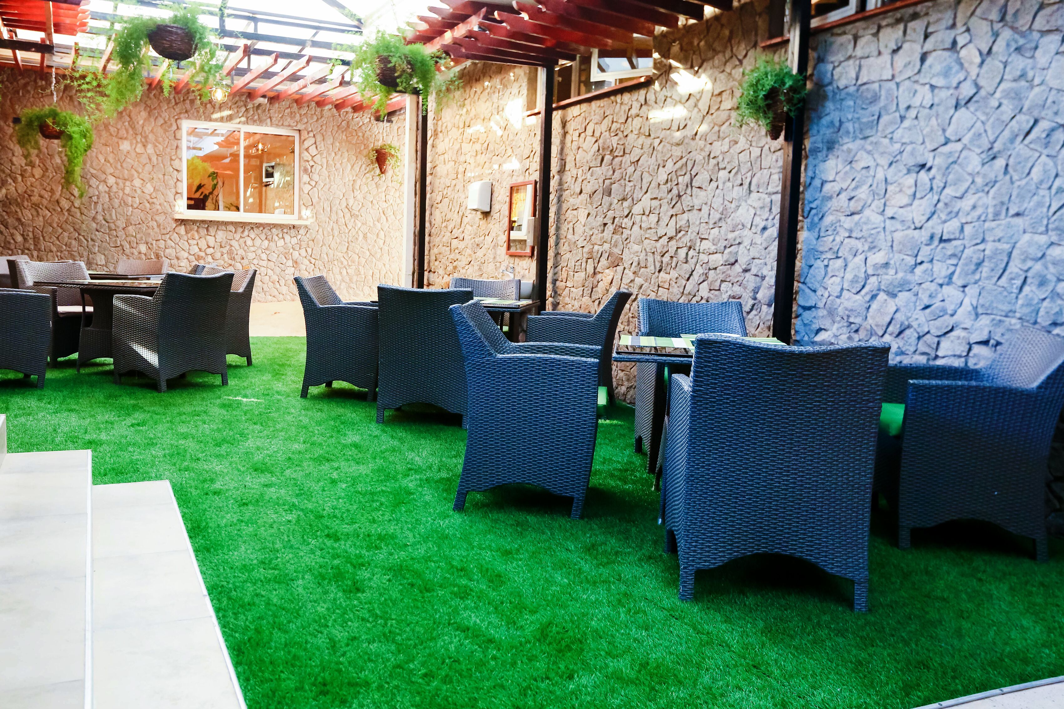Une terrasse extérieure avec des meubles en osier et un mur en pierre.