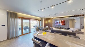 Una sala de estar moderna con comedor, ventanas amplias y un televisor de pantalla plana.