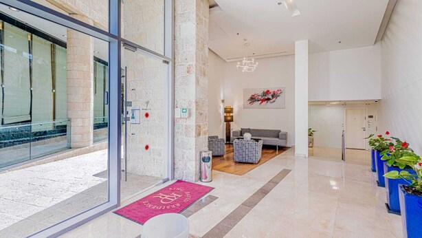 Un moderno vestíbulo de hotel con mostrador de recepción, zona de estar y una escalera que conduce a los pisos superiores.