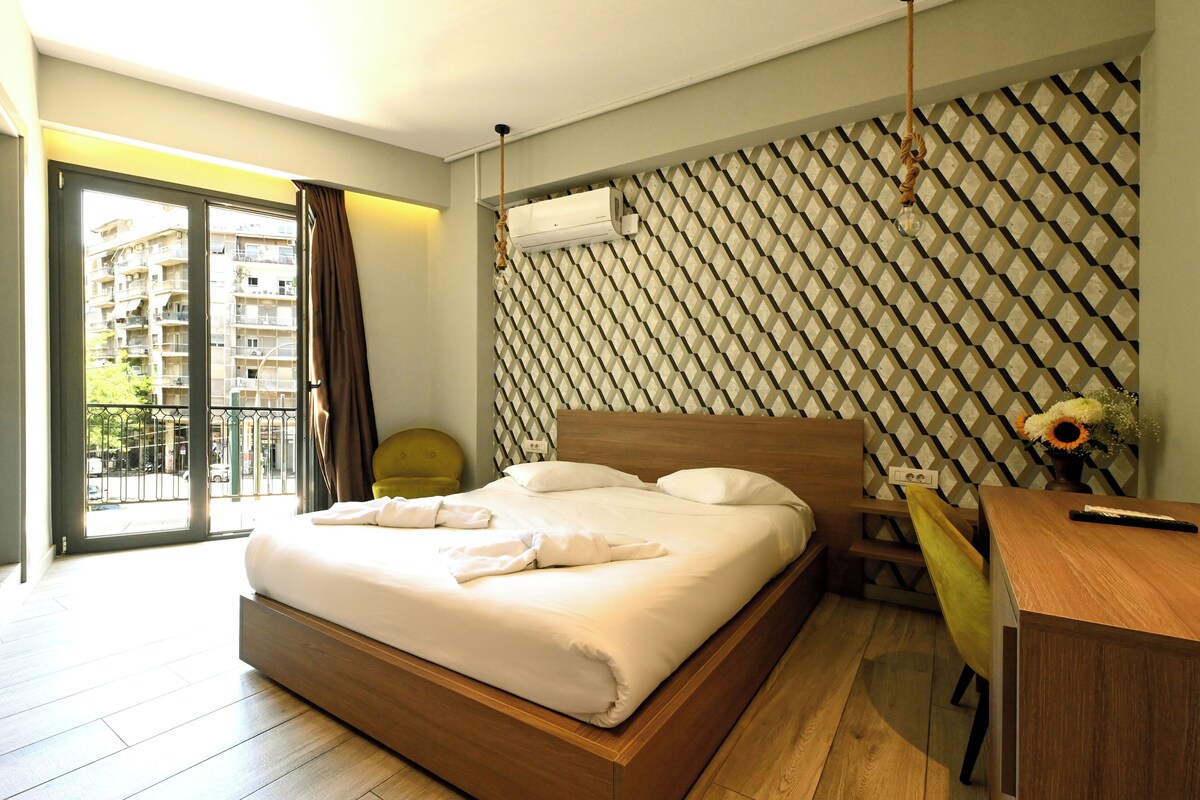 Ein modernes Hotelzimmer mit einem großen Bett, einem Schreibtisch und Blick auf den Balkon.