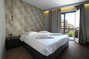 Camera d'albergo con un letto grande, un comodino, una lampada a parete e vista sul balcone esterno.