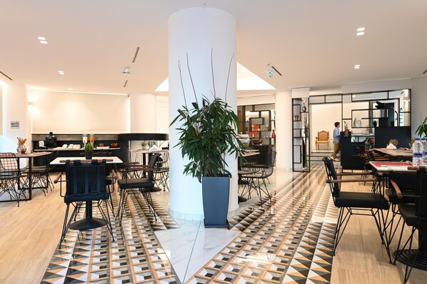A modern dining area with a central column, black chairs, and a patterned floor.