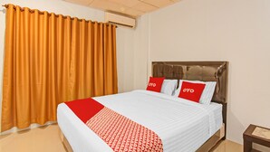 Une chambre d’hôtel équipée d’un lit, de rideaux, d’un climatiseur et d’une table de chevet.