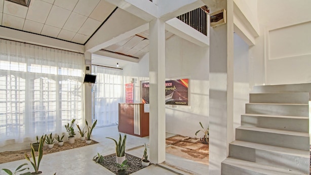 Un hall d’hôtel avec un escalier, des plantes en pot et un comptoir d’accueil.