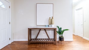 A hallway with a wooden console table, a framed artwork, decorative vases, and a potted plant. - Charming and Amaizing Home with Pool in Miramar (Miramar)
