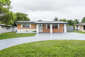 A modern two-story house with a brick facade, a flat roof, and a paved driveway leading to a front door.