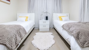 A twin bedroom with two beds, a white rug, and a nightstand between them. - Charming and Amaizing Home with Pool in Miramar (Miramar)
