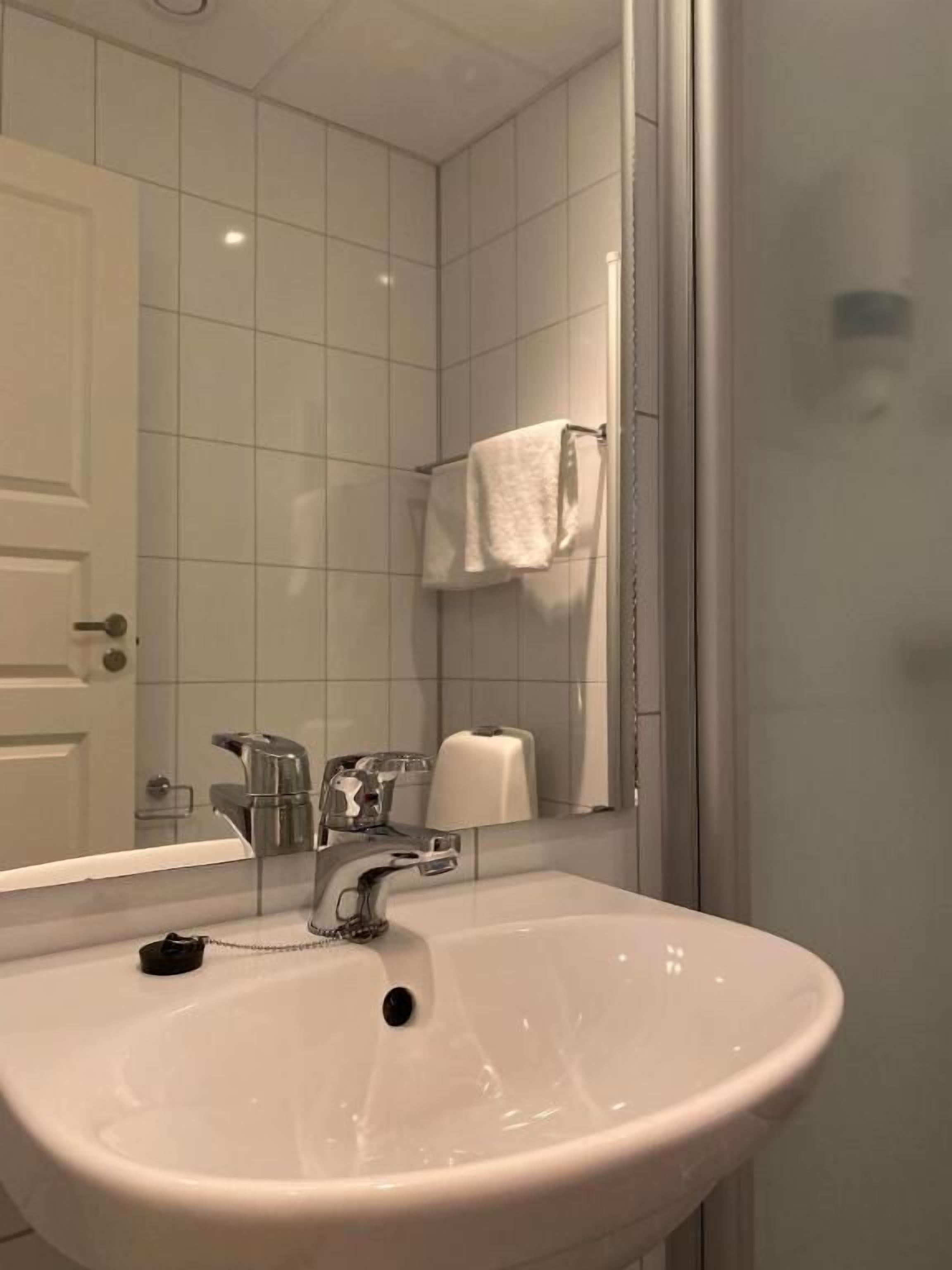 Un baño con un lavabo blanco, un espejo y una toalla colgada en la pared.