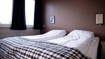 A hotel room with a large bed, a window with curtains, and a wall-mounted picture.
