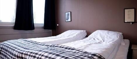 Una habitación de hotel con una cama grande, una ventana con cortinas y un cuadro colgado en la pared.