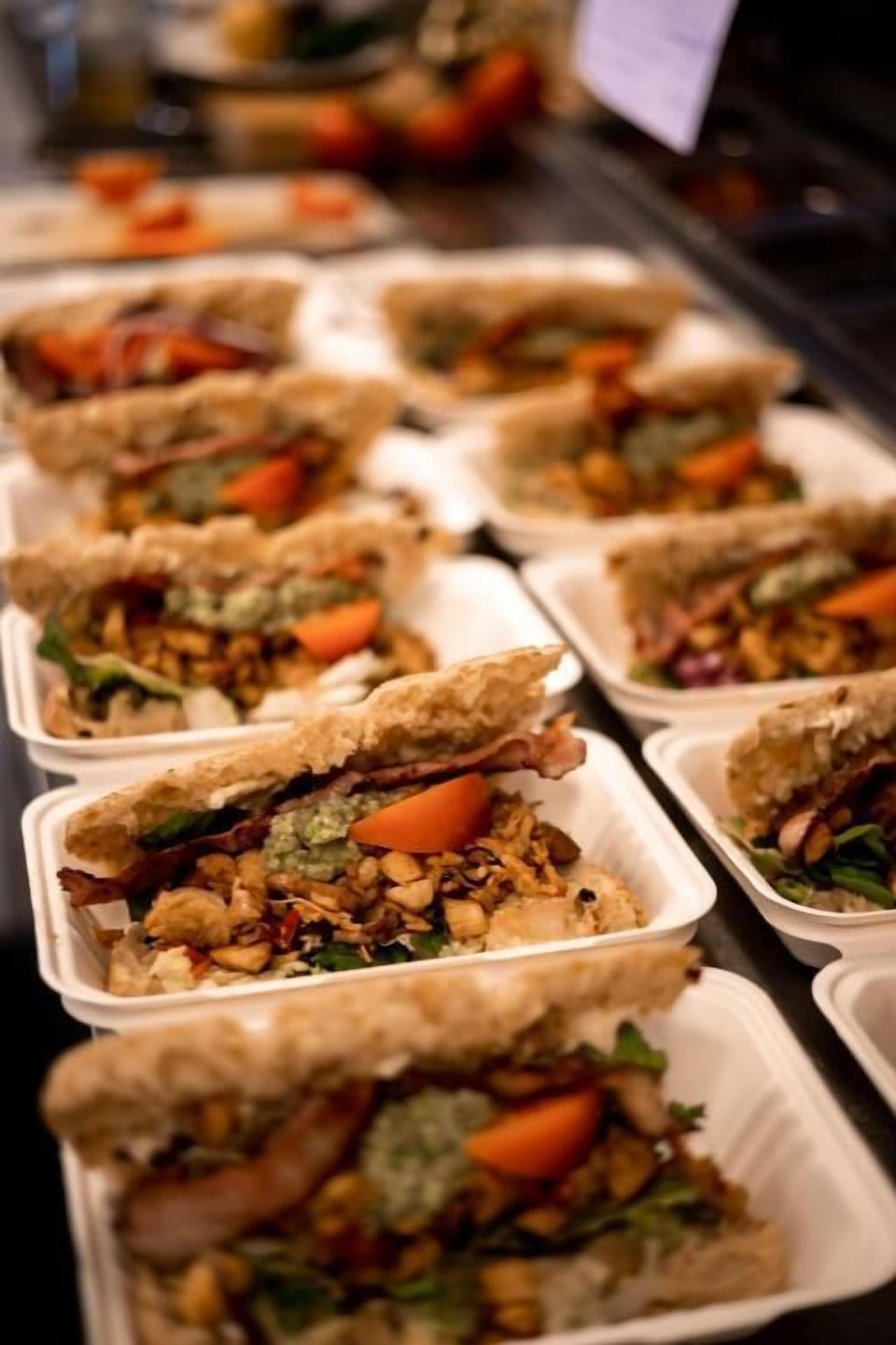 A row of food containers with sandwiches.