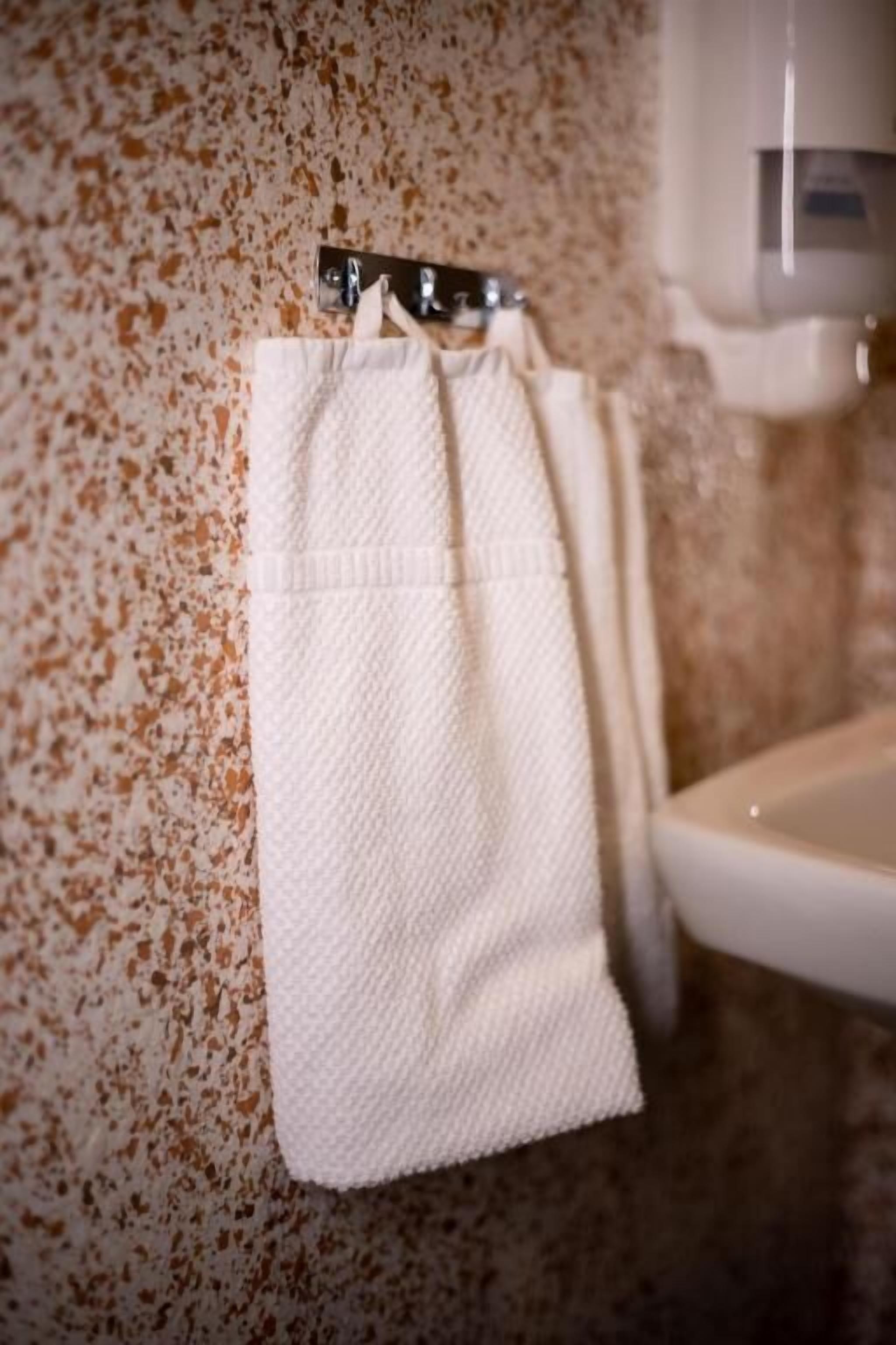 A bathroom with a white towel hanging on a metal towel rack and a white sink.