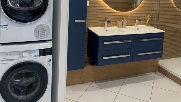 Ein modernes Badezimmer mit eingebauter Waschmaschine und Trockner, einem Waschtisch mit Spiegel und Holzvertäfelung.