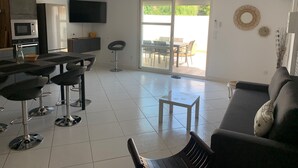 Eine moderne Küche mit Essbereich, einer Couch und einem Fernseher.