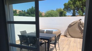 Eine Terrasse mit Glastür, einem Tisch, Stühlen und einem aufblasbaren Whirlpool.