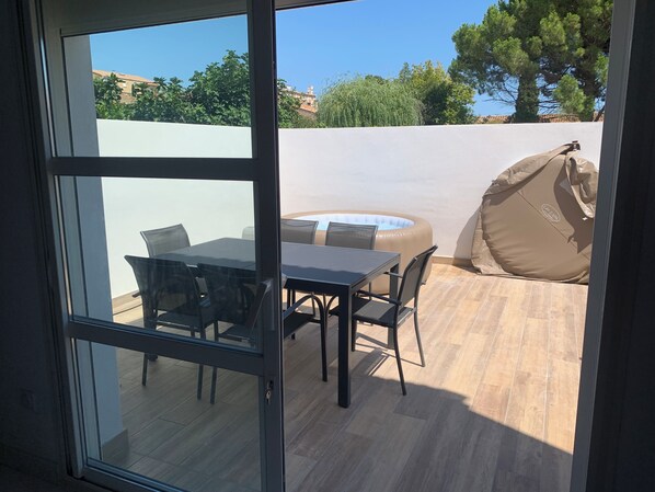 A patio with a glass door, a table, chairs, and an inflatable hot tub.