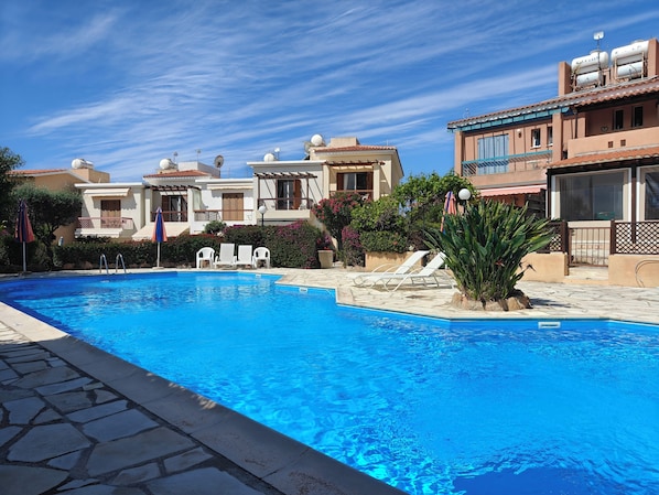 A swimming pool with lounge chairs and a stone deck.