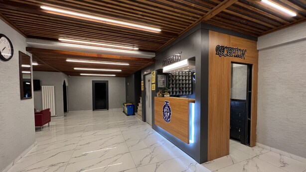 A reception area with a wooden reception desk, marble flooring, and a clock on the wall. - Hotel Prima (Istanbul)