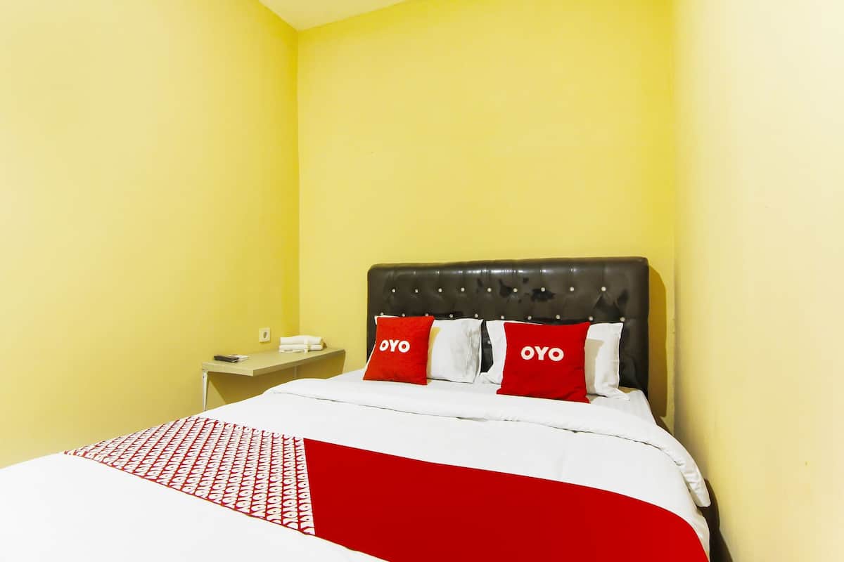 Quarto de hotel com uma cama, uma mesa de cabeceira e uma parede com esquema de cores amarelo.