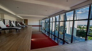 Eine moderne Hotelhalle mit rotem Teppich, Lounge-Sesseln und großen Fenstern mit Blick auf die Stadt.