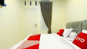 Una habitación de hotel con una cama, un cabecero gris y una puerta blanca.