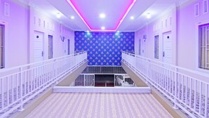 Pasillo de hotel con pared de diseño azul, barandas blancas y una escalera que sube a un nivel superior.