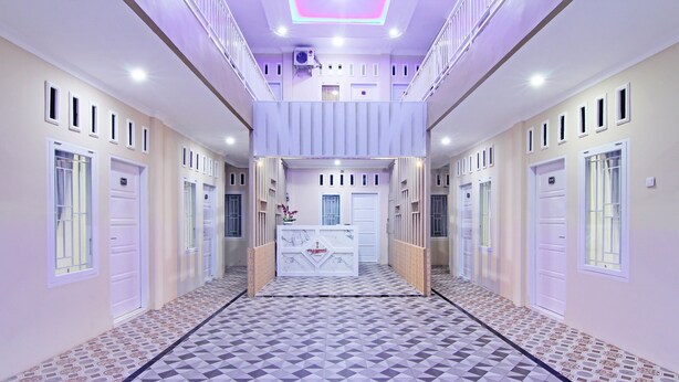 Un pasillo con suelo de diseño geométrico, puertas blancas y un mostrador de recepción central.