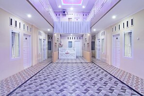 A hallway with a geometric patterned floor, white doors, and a central reception desk.