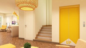 En moderne hotellobby med et trægulv i fiskebensmønster, en trappe, en receptionsdisk og en lys gul elevator.