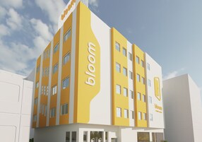 Een modern gebouw met het 'bloom'-logo, uitgevoerd in geel en wit, met meerdere verdiepingen en een plat dak.