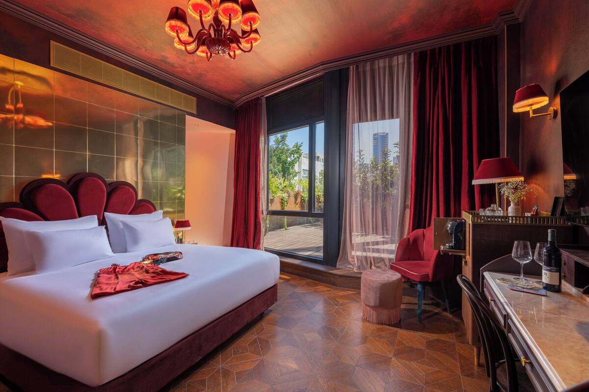 Quarto de hotel com uma cama grande, área de refeições e vista para o exterior.