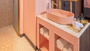 Et badeværelse med en pink vask, et spejl og en håndklædestang.