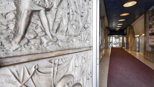 A corridor with a detailed stone relief sculpture on the wall and a red carpeted floor. - Chic Modern Lofts by Wonderful Italy (Genoa)