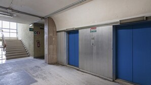 A hallway with a staircase, blue doors, and a fire extinguisher. - Chic Modern Lofts by Wonderful Italy (Genoa)