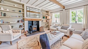 A cozy living room with a fireplace, comfortable seating, and a bookshelf.