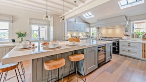 A spacious kitchen with a large island, pendant lights, and a skylight.