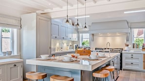 A modern kitchen with a large island, bar stools, and pendant lighting.
