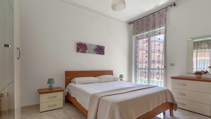 Een slaapkamer met een bed, nachtkastjes, een spiegel en een raam met gordijnen.