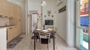 Een moderne keuken met houten keukenkastjes, een eettafel gedekt voor vier personen en een televisie op een meubel.