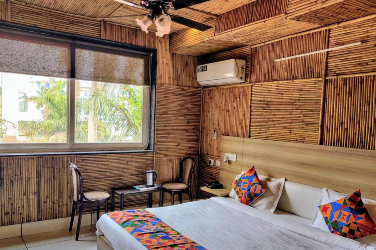 Ein Zimmer mit einem großen Bett, einem Fenster mit Blick auf Palmen, einem Deckenventilator und einer Klimaanlage.