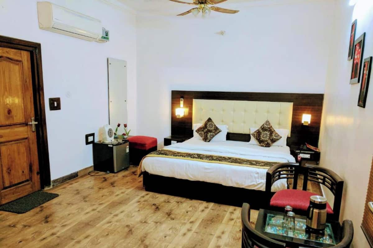 Ein Hotelzimmer mit einem Bett, Nachttischen, einem Schreibtisch mit Stuhl, Holzboden und Deckenventilator.