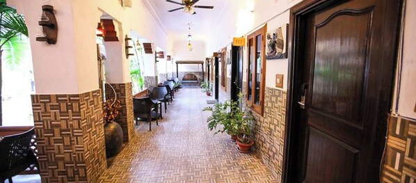 A hallway with patterned flooring, a ceiling fan, and a door on the right.