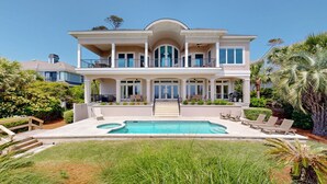 Ein zweistöckiges Haus mit Swimmingpool, überdachter Terrasse und gepflegtem Garten.