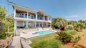 Ein zweistöckiges Haus mit großem Pool, einer Holzterrasse und einem angelegten Garten.